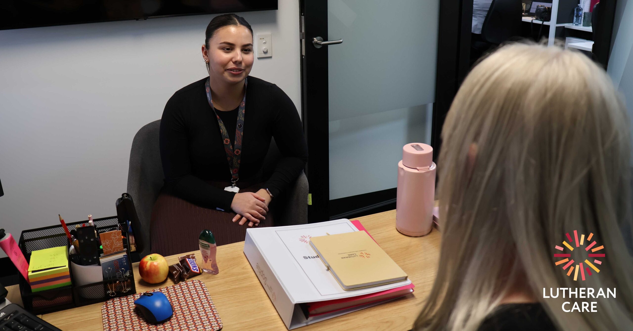 Image of placement student Sophie talking with her supervisor at Lutheran Care. The Lutheran Care logo appears in the bottom right hand corner.