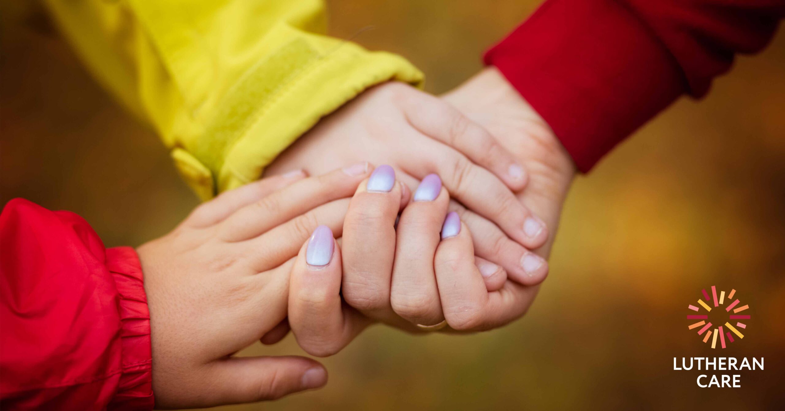 A mother and her two children hold hands. The Lutheran Care logo appears in the bottom right hand corner.