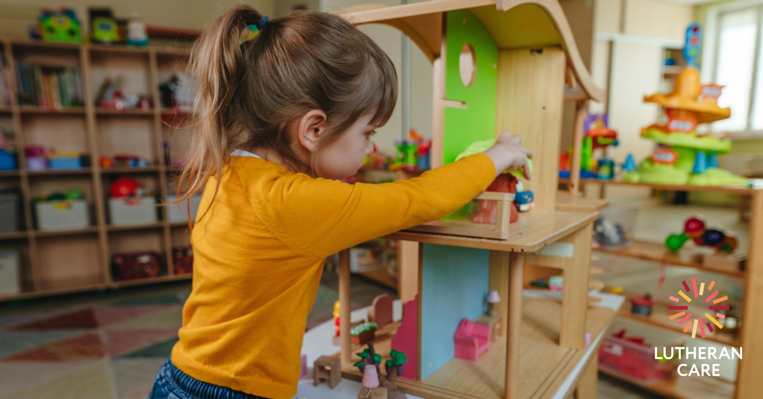 A young girl plays with a dolls' house. The Lutheran Care logo appears in the bottom right hand corner.