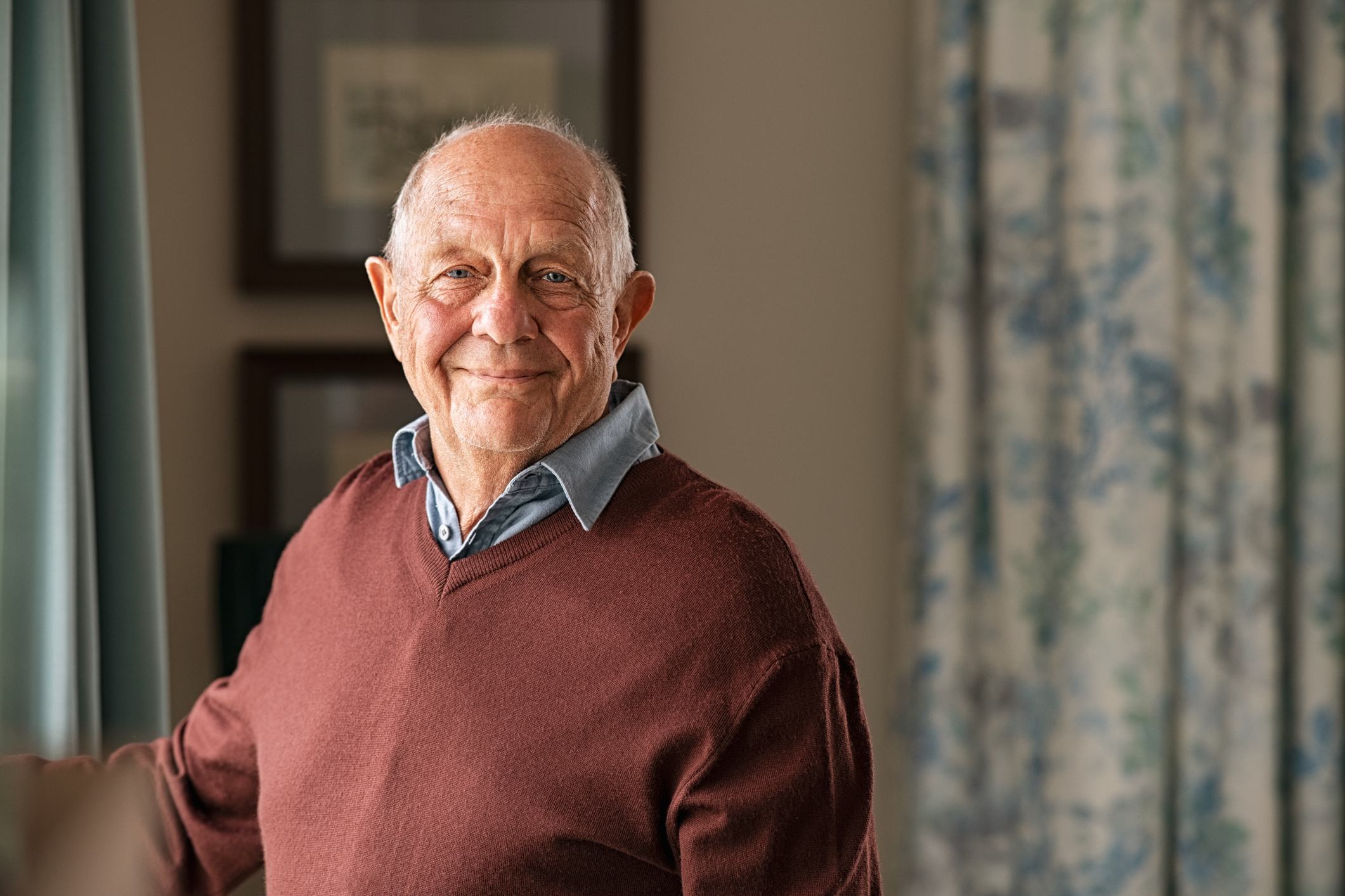 Portrait of happy retired senior man standing at home.