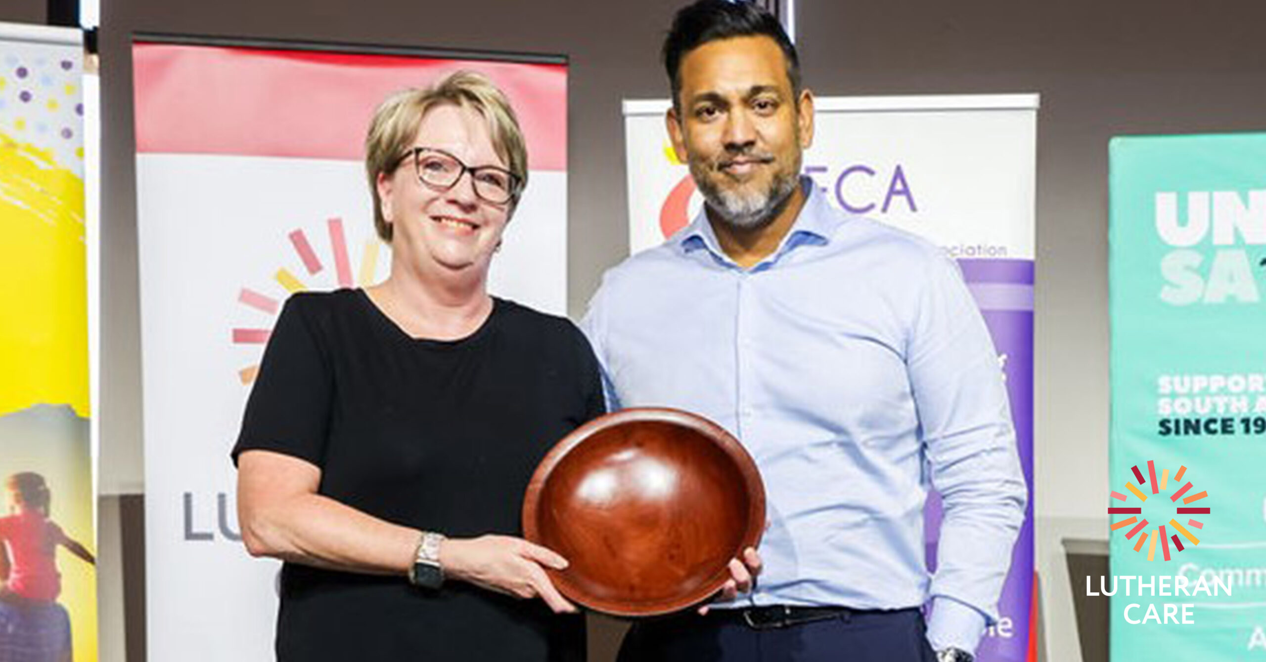 Lutheran Care CEO Rohan Feegrade presenting the award to the SAFCA winner. The Lutheran Care logo appears in the bottom right hand corner.