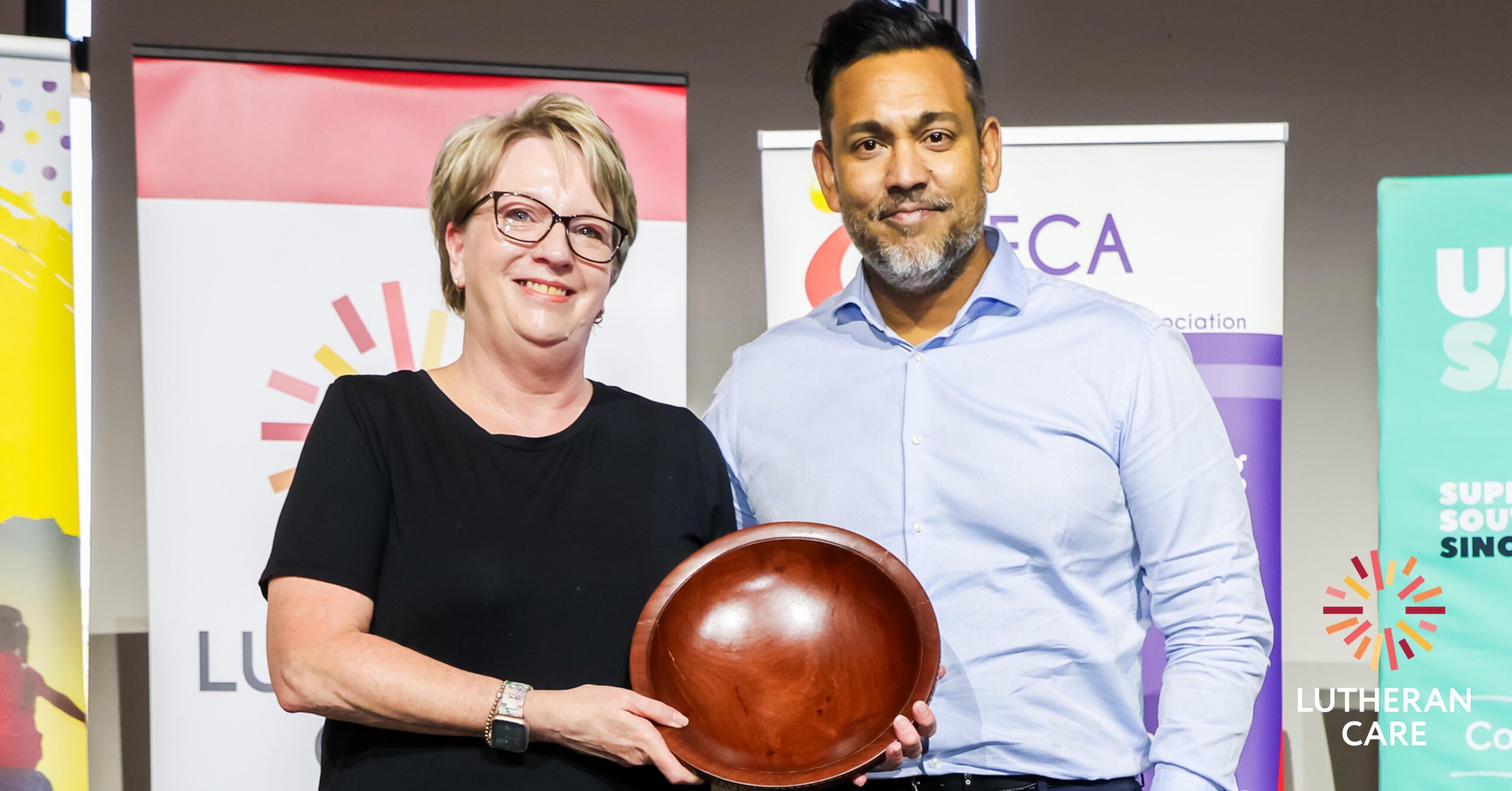 Lutheran Care CEO Rohan Feegrade presenting the award to the SAFCA winner. The Lutheran Care logo appears in the bottom right hand corner.