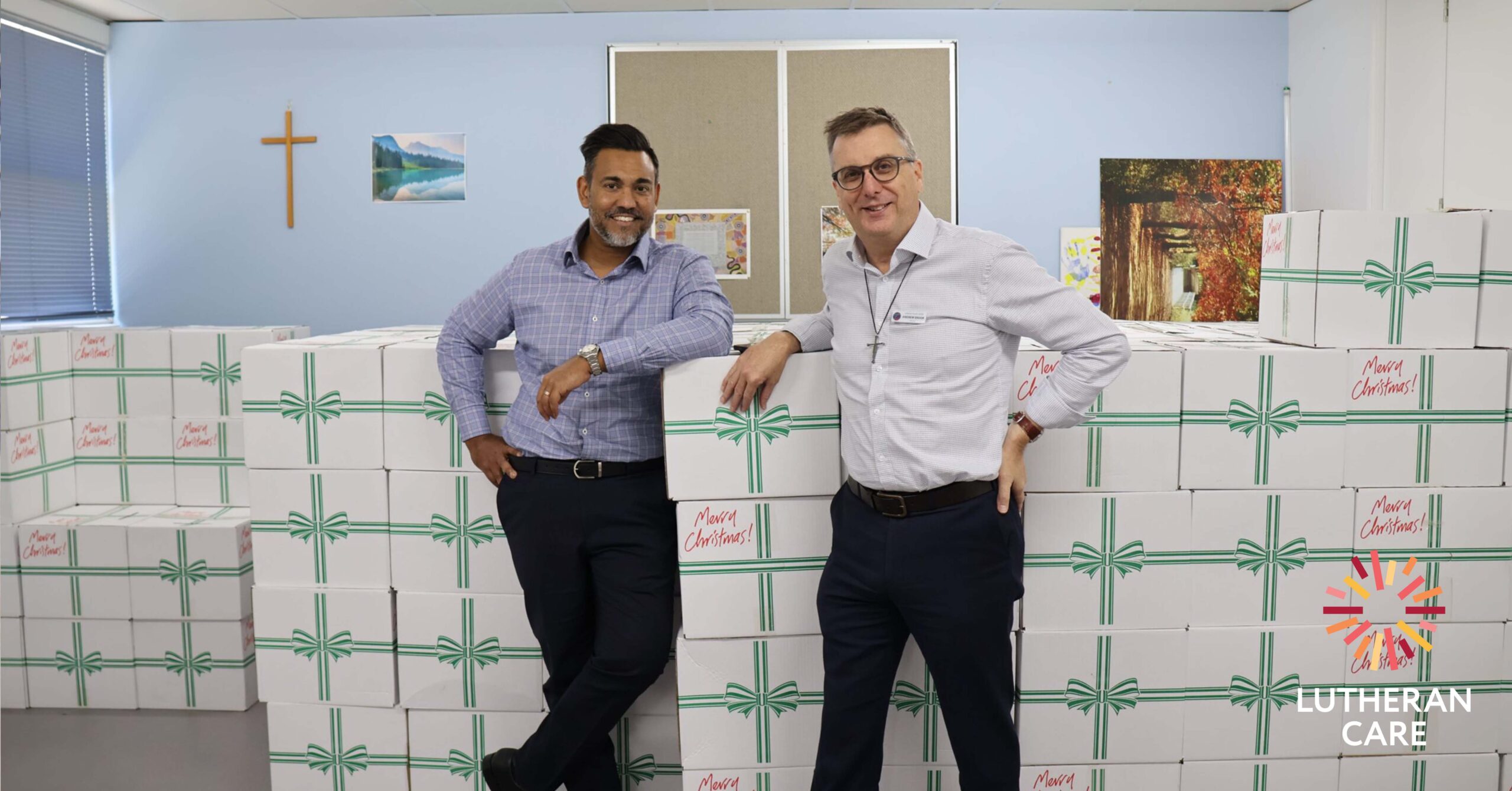 Lutheran Care CEO Rohan Feegrade and Lutheran Church of SA/NT Bishop Andrew Brook with Christmas Hampers. The Lutheran Care logo appears in the bottom right hand corner.