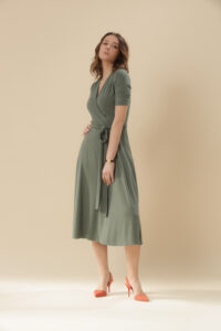 Studio photo of young female model in green viscose wrap dress.